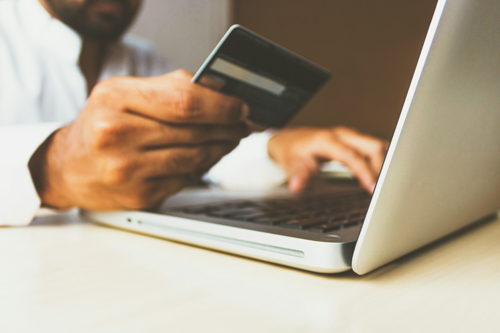 A person holding a bank card while working on a laptop, illustrating a funding and withdrawal interaction on a screen